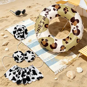 Kids cow print bikini swimsuit set with hat sunglasses and cute swim ring for beach vacation.