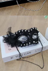 Black lace masquerade mask detail, featuring delicate pearls, rhinestones and side flower decoration.