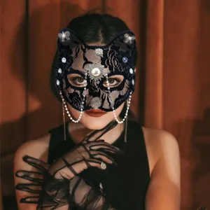 Primo piano di maschera da gatto in pizzo nero con strass lucidi e perle pendenti.
