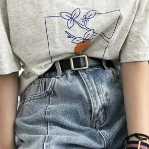 Gedetailleerd shot van een stijlvolle zwarte smalle riem gecombineerd met jeans en een t-shirt.