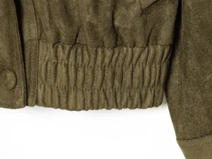 Close up view of olive green faux suede jacket elastic hem and sleeve texture detail.