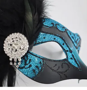 Primo piano dettagliato della maschera con glitter blu, piume nere e strass brillanti.
