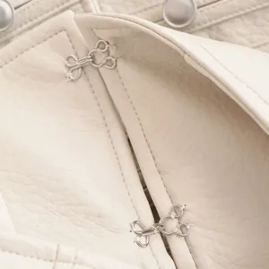 Gros plan détaillé d'une veste en similicuir blanc avec fermoirs métalliques et coutures.