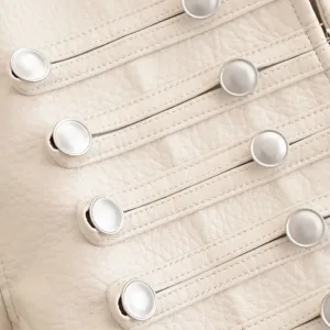 Gros plan détaillé d'une veste en similicuir crème avec coutures passepoilées et boutons.