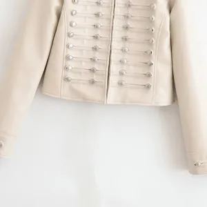 Détail de veste en similicuir blanc cassé avec boutons métalliques et cordons militaires.