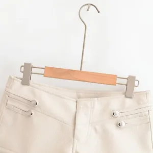 Gros plan sur le short femme en similicuir crème avec boutons décoratifs et surpiqûres.