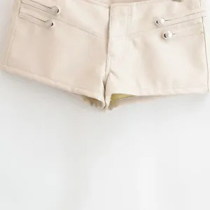 Détail de short en similicuir beige avec boutons métalliques chics et finitions soignées.