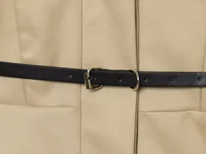 Vue détaillée du trench-coat minimaliste pour femme avec ceinture noire et boucle.