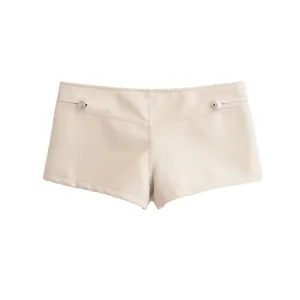 Vue rapprochée de short en similicuir beige avec boutons métalliques argentés et poches.