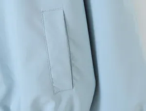 Light blue women trench coat jacket pocket detail closeup, stylish casual outerwear fabric.