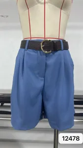 Detalle de pantalones cortos plisados de cintura alta azul, con cinturón tejido y hebilla elegante.