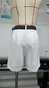 Vista detallada de pantalones cortos blancos de tiro alto con pliegues y cinturón marrón.