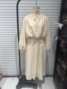 Detailed view of a beige ruffle collar blouse and skirt set on mannequin in studio.