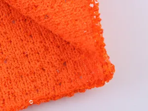 Nahaufnahme von orangenem Strickgewebe mit Metallicfaden und funkelnden Pailletten dekoriert