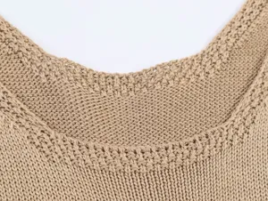 Detailed view of women's beige knit tank top collar, fine knitting texture and design.