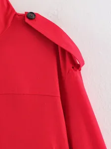 Red trench coat detail view showing stylish shoulder epaulet and black button decoration.