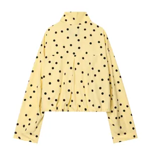 Detailed view of yellow long-sleeve high-collar jacket featuring black polka dots and back pleat.