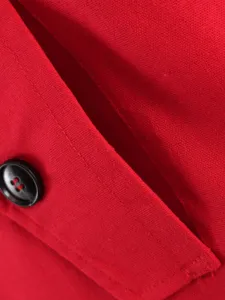 Detailed view of red cotton linen trench coat pocket and button trim with fine texture.