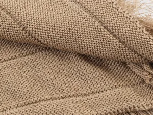 Detailed close-up shot of brown knitted fabric texture featuring elegant fringe trim elements.