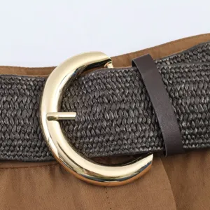 Detalle de cinturón trenzado, correa marrón con hebilla redonda dorada grande para pantalones cortos.