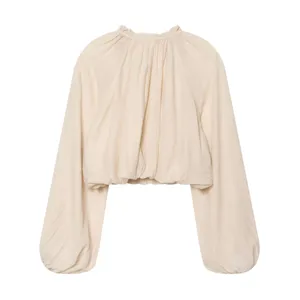 Detail shot of beige ruffle high neck balloon sleeve blouse, loose fit textured fabric top.