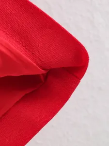 Close-up detail of red cotton linen trench coat fabric showing fine stitching texture.