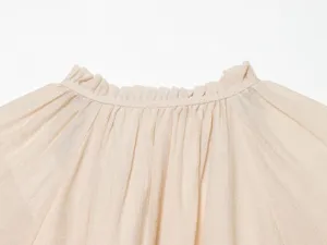 Close-up detail of the elegant ruffle collar and gathered pleats on the women's beige blouse.