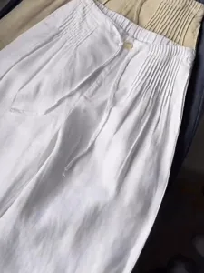 Detailed view of white cotton casual pants with elastic drawstring waist and elegant straight leg design.