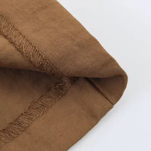 Primer plano de costuras de prenda de tela marrón, textura de puntada limpia.