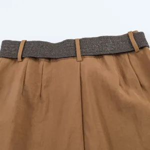 Primer plano detallado de pantalones cortos plisados de talle alto con cinturón tejido.