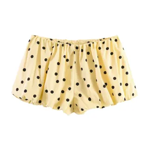 Detailed close-up of yellow summer shorts featuring playful black polka dots and cute puffy design.