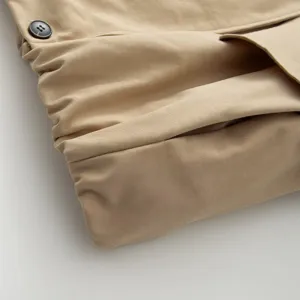 Close-up detail of women's khaki trench coat featuring fine fabric texture and button accent.
