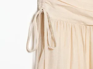 Beige textured apparel detail close-up showing exquisite ruched drawstring design.