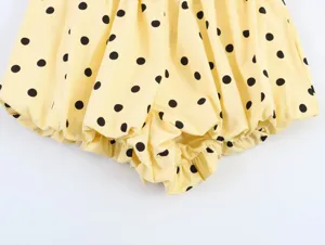 Close-up detail of yellow black polka dot women shorts, pleated elastic hem fabric texture.