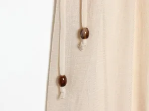 Close-up detail of beige textured fabric with chic drawstring and marbled beads.