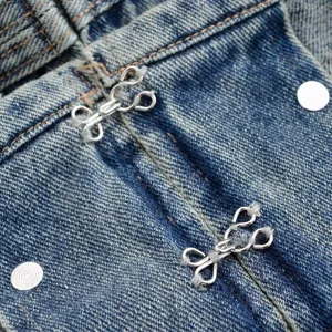 Close-up of denim clothing metal hook-and-eye fastener detail, durable stitching and hardware.
