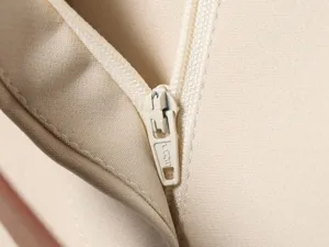 Gros plan détaillé de la fermeture éclair et de la texture du tissu d'un pantalon beige.