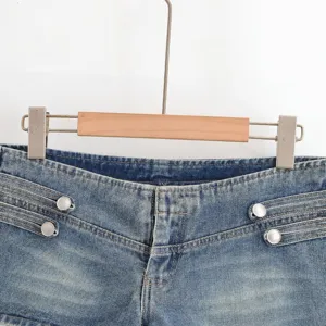Close-up of high-waist denim shorts waistband with stylish double metal button design.