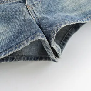 Detailed view of women's blue denim shorts featuring raw frayed hem and vintage wash finish.