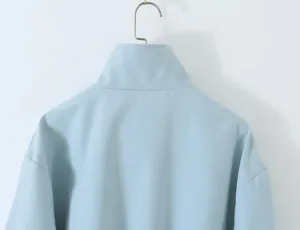 Back collar detail of light blue loose casual work jacket, clean solid background.