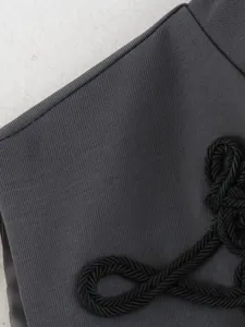Detailed view of slim sleeveless vest fabric featuring elegant black rope knot embroidery accent.