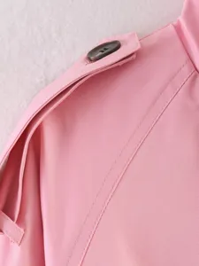 Detailed close-up of women pink trench coat shoulder epaulet and dark button design.
