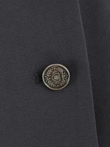 Detailed close-up view of dark gray twill fabric featuring a vintage metallic embossed button.