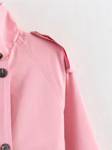 Close-up detail of women pink stand collar trench coat shoulder and button design.