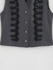 Close-up of dark grey women's sleeveless vest featuring black braided cord trim and metallic buttons.