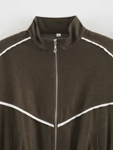 Close-up detail of women brown mock neck zip-up jacket with white contrast piping trim.