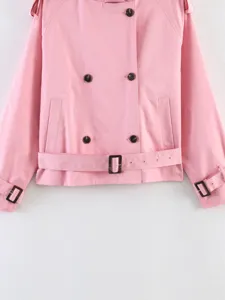 Pink short trench coat detail showing double breasted buttons and stylish waist belt design.