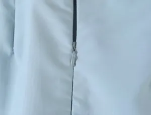 Close-up view of the smooth front zipper and fine fabric texture on the light blue coat.