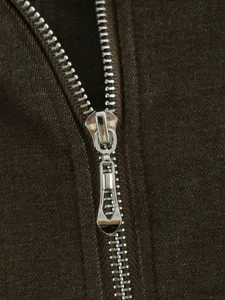 Close-up detail of silver metal zipper on dark brown jacket fabric, clear texture.