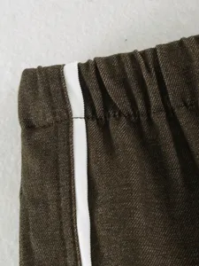 Brown trousers detail shot, casual pants side stripe design, premium fabric texture.